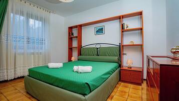 Une chambre à coucher comprenant un lit, une table de chevet, une commode et une étagère.