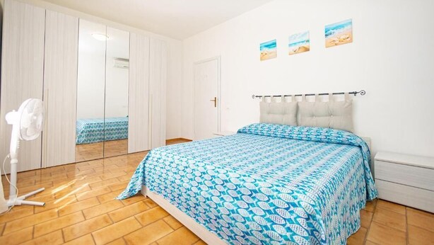 Ein Schlafzimmer mit Bett, Kleiderschrank und Ventilator.