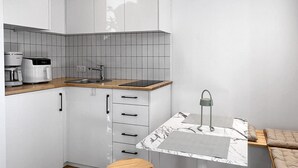 A modern kitchen with white cabinets, a wooden countertop, a coffee maker, and a table with stools. - Modern Seaside Home with Private Patio + Parking - Blue Zone Homes (Olimpiaki Akti)