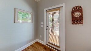 A hallway with a wooden floor, a door with blinds, a framed picture on the wall, and a wall-mounted clock. - Alpine Village Condo E| Location, Location, Location, Across From RIver and Tubing!! (Helen)
