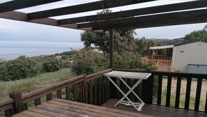 Une terrasse en bois avec une table et une table pliante blanche.