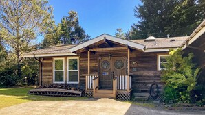 A wooden house with a front porch, a garage, and a driveway.