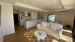 Un salon moderne avec un canapé blanc, une petite table ronde et un tapis à carreaux.