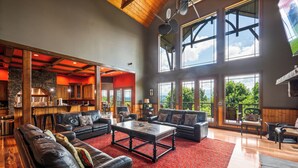A spacious living area with a red carpet, leather sofas, and a large window offering a view of the outdoors.