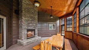 A wooden interior with a stone fireplace, wooden benches, and large windows.