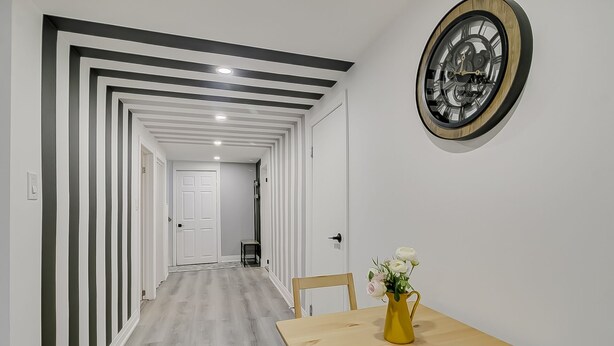 A hallway with a modern design, featuring a wooden floor and a white door at the end. - TorontoGEM: 20 mins to Downtown,10 mins to Airport (Toronto)