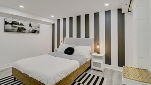 A modern bedroom with a bed, bedside tables, a picture on the wall, and a striped rug. - TorontoGEM: 20 mins to Downtown,10 mins to Airport (Toronto)