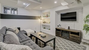 A modern living room with a sectional sofa, a coffee table, a fireplace, and a TV mounted on the wall. - TorontoGEM: 20 mins to Downtown,10 mins to Airport (Toronto)