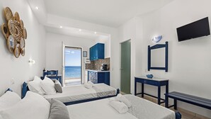 A hotel room with two beds, a desk, a TV, and a view of the sea. - ammos stegna studios  (Rhodes)