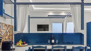 A dining area with a white table, blue chairs, and a blue accent wall. - ammos stegna studios  (Rhodes)