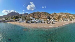 A coastal town with clear turquoise waters, white buildings, and a mountainous backdrop. - ammos stegna studios  (Rhodes)
