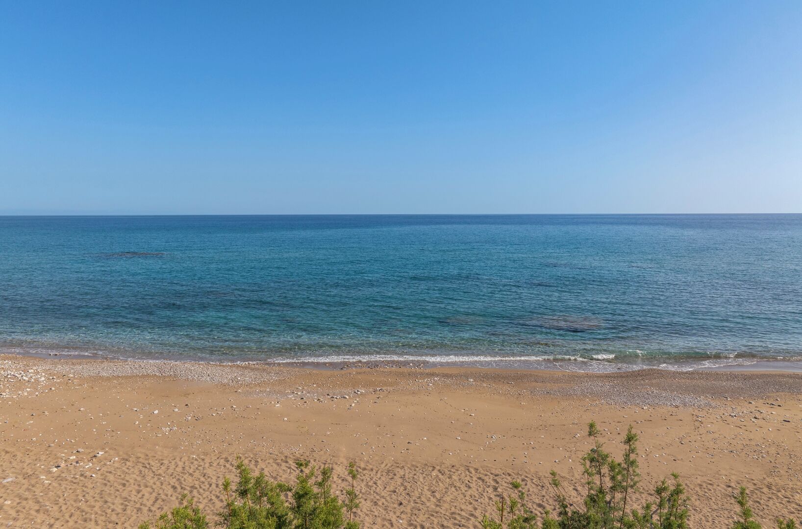 Une plage avec une eau d’un bleu limpide et un rivage sablonneux.