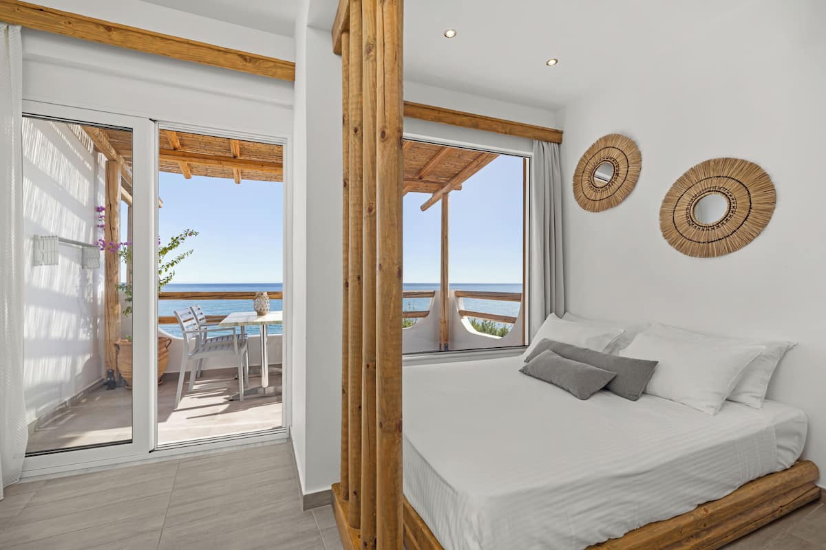 Un dormitorio con una cama grande, un balcón con vistas al mar y dos adornos tejidos en la pared.
