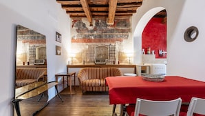 A cozy dining area with a red tablecloth, striped sofa, and wooden flooring. - Pepi 64 in Firenze With 2 Bedrooms and 1 Bathrooms (Florence)