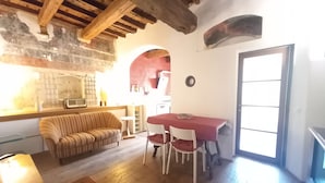 A cozy room with a wooden ceiling, a sofa, a dining table with chairs, and a kitchen area with a sink and a radio. - Pepi 64 in Firenze With 2 Bedrooms and 1 Bathrooms (Florence)