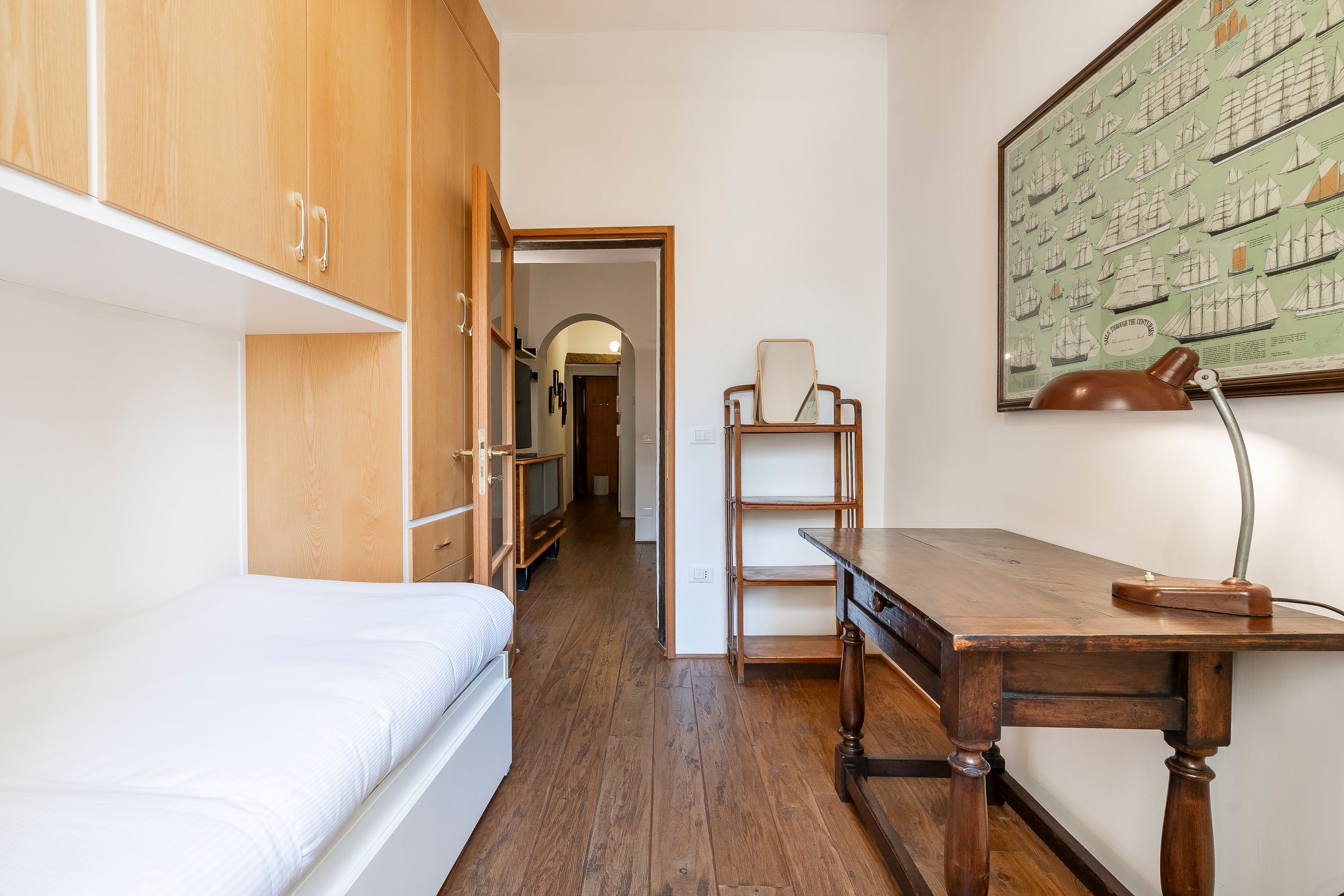 Een kamer met een houten stapelbed, een bureau met een lamp en een inlijsting kaart aan de muur.