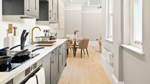 A modern kitchen with a central island, a dining area with a table and chairs, and a window providing natural light. - THE FORBURY  (Reading)