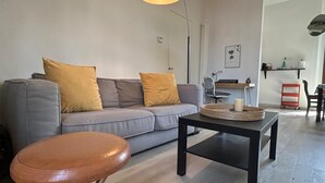 A modern living room with a grey sofa, two mustard-colored cushions, a black coffee table, and a leather stool. - La Corte di San Domenico (Pisa)