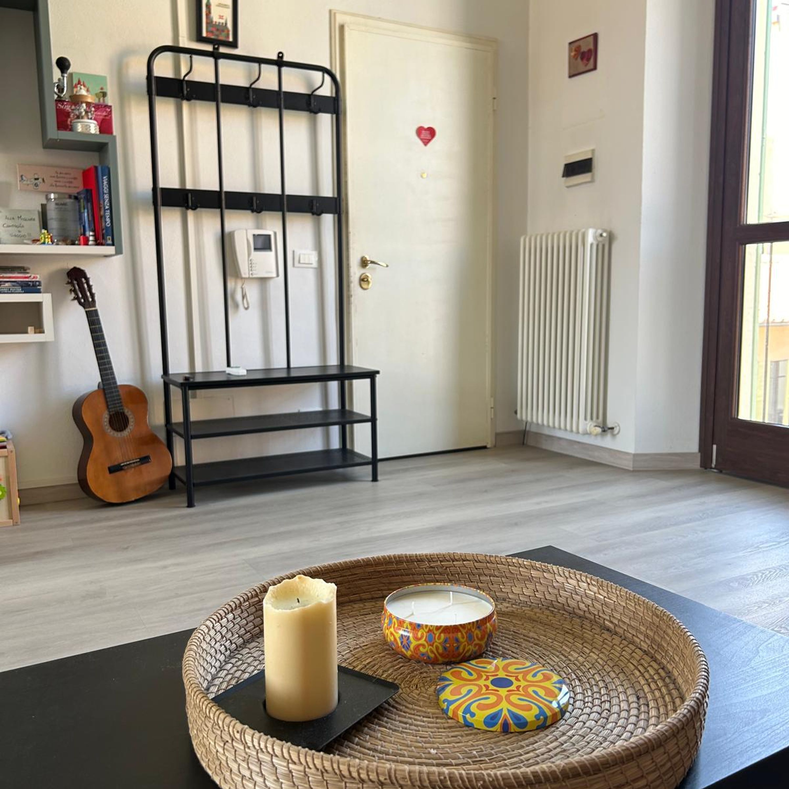 Una stanza con una chitarra, una sedia, un termosifone e una porta decorata con un cuore.
