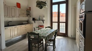 A kitchen with a dining table, chairs, cabinets, and a large window. - La Corte di San Domenico (Pisa)