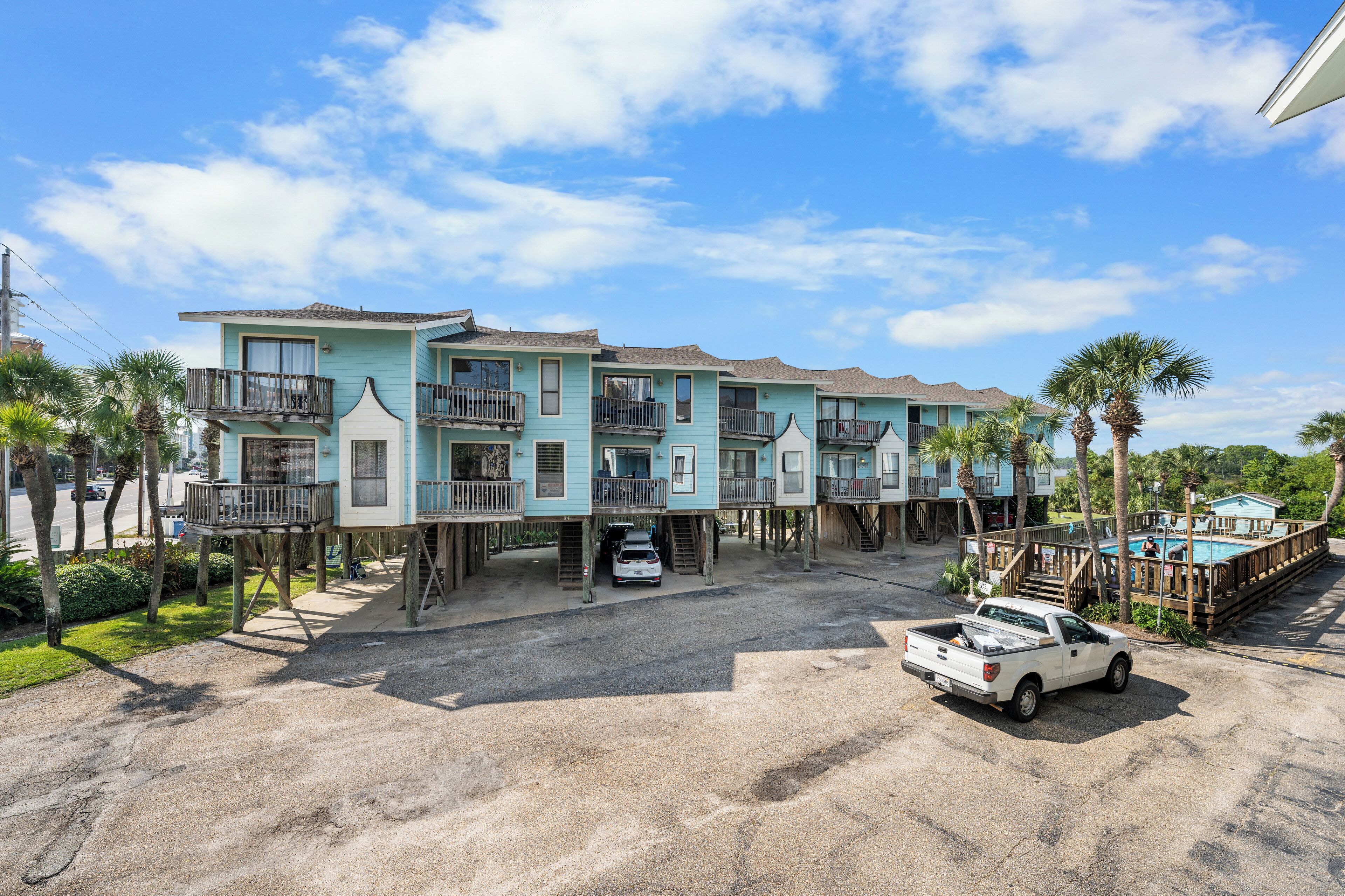 A beachfront property with multiple blue buildings, a white truck, and a pool area.