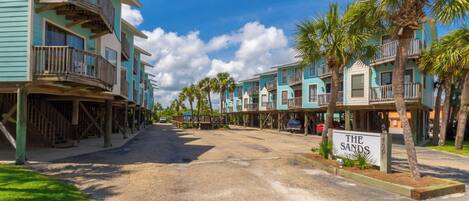 A beachfront hotel with multiple-story buildings, balconies, and palm trees.