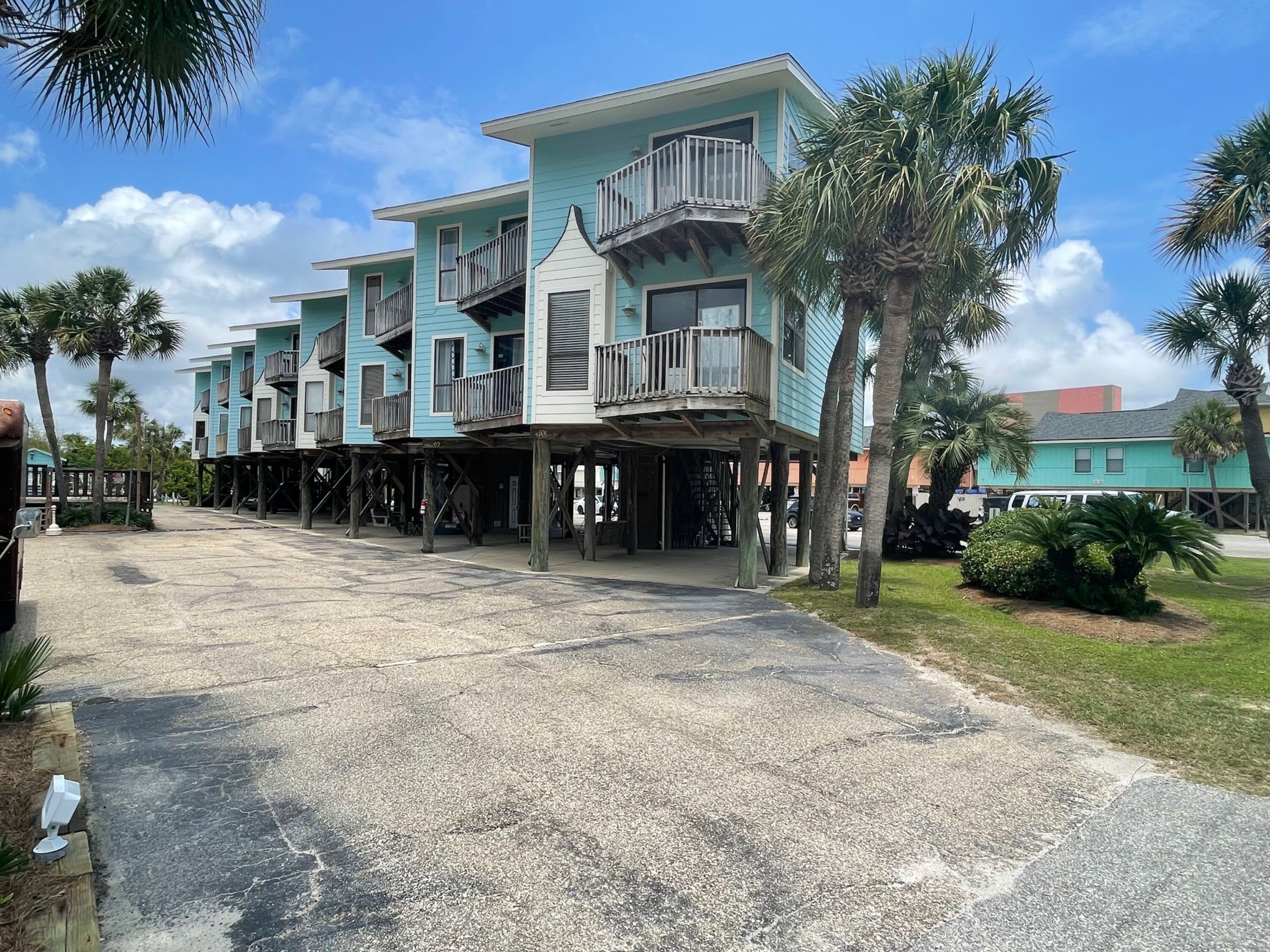 A beachfront hotel with multiple-story buildings, outdoor balconies, and palm trees.
