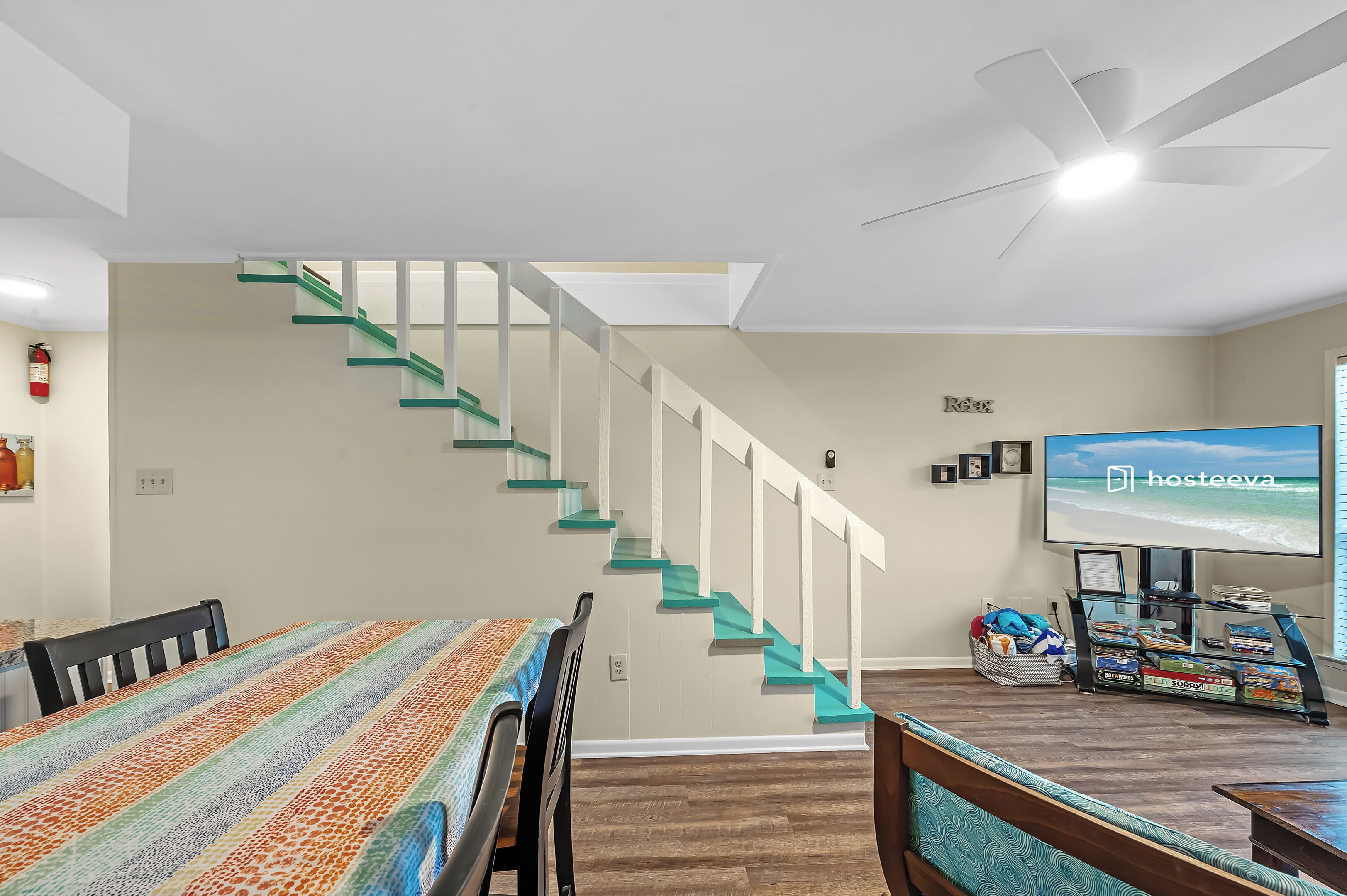 A living room with a striped table, a staircase, a television, and a bookshelf.