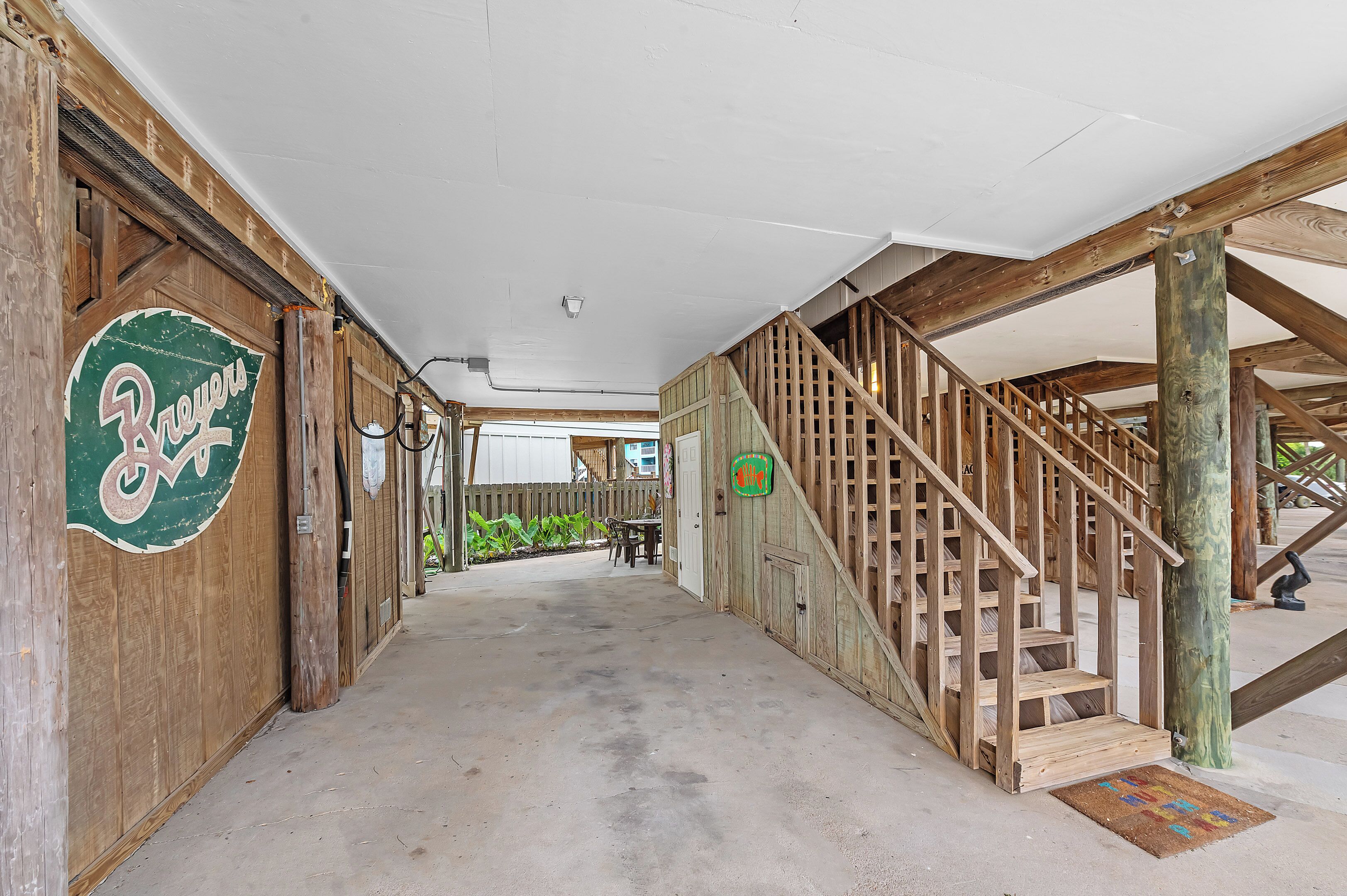 A wooden interior with a staircase, a door labeled "Brewers," and a concrete floor.