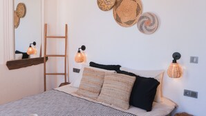 Ein Schlafzimmer mit Bett, Kissen, einer Leiter, Wandleuchten und dekorativen Wandbehängen.