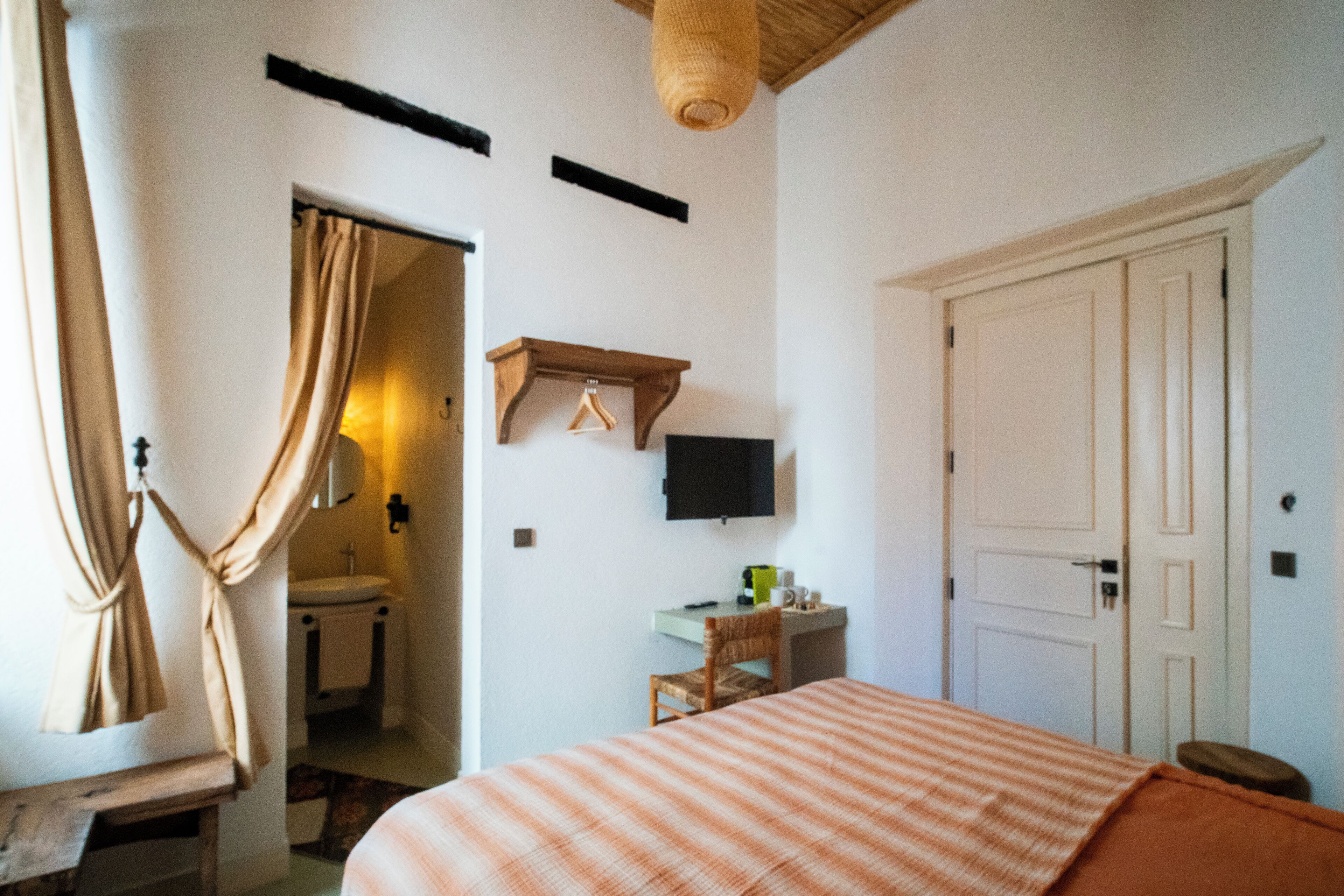 Een slaapkamer met een bed, een bureau, een stoel, een televisie en een deur.