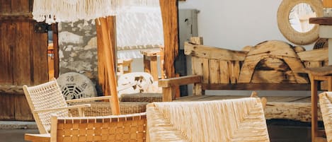 A rustic interior with wicker furniture, a stone wall, and a wooden bench.