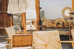 Un interior rústico con muebles de mimbre, una pared de piedra y un banco de madera.