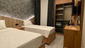 A modern hotel room with two wooden beds, a built-in TV, and a minibar. - OTEL ORTADOĞU (Sanliurfa)