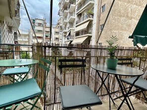 Un balcon extérieur avec une clôture en bambou, une petite table et deux chaises.