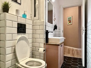 Une salle de bain moderne équipée de toilettes, d’un lavabo et d’un espace douche.