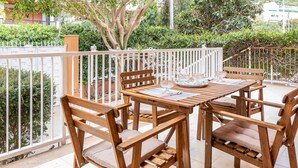 An outdoor patio with a wooden table and chairs, surrounded by a white fence and lush greenery. - Addaura Seaview Apartment by Wonderful Italy (Palermo)
