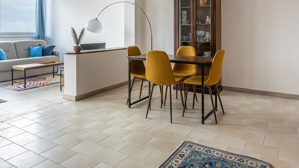 A dining area with a table and chairs, a cabinet with glass doors, a sofa, and a window with curtains. - Addaura Seaview Apartment by Wonderful Italy (Palermo)