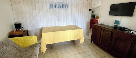A room with a bed, a sofa, a table, a TV, and a cabinet.
