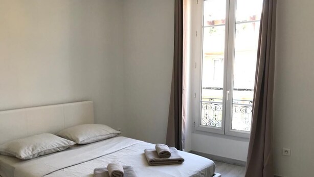 Un dormitorio con cama, almohadas y una ventana con cortinas.