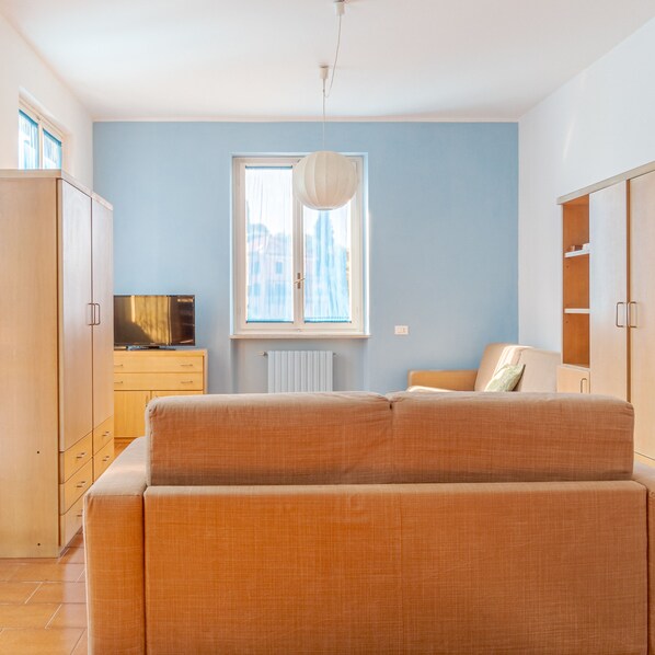 A modern living room with a sofa, a television, and a window with curtains.