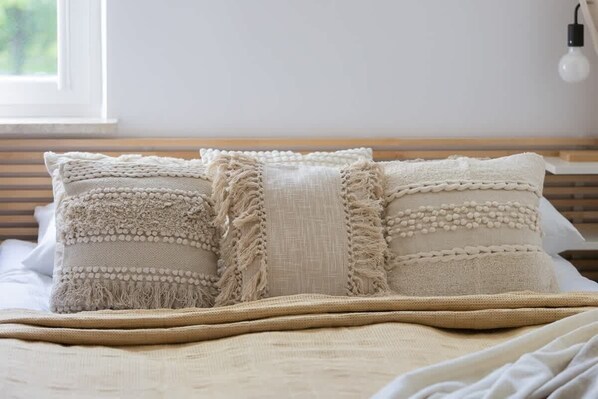 Un lit avec des oreillers de couleur beige et une couverture tissée.
