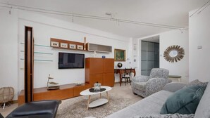 Un salon moderne comprenant un canapé, une table basse, un téléviseur et un miroir décoratif.