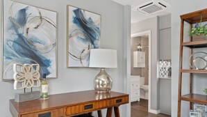 A modern living room with a wooden coffee table, a white lamp, and abstract paintings on the wall.