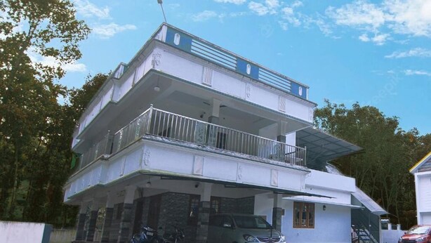 A two-story residential building with a balcony on the upper floor, a covered parking area, and a bicycle parked outside.