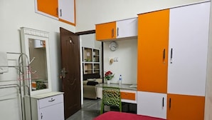 A bedroom with a bed, a desk, and a wardrobe.