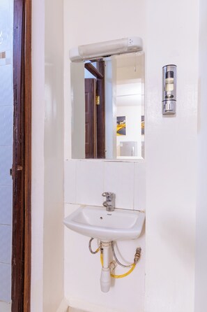A bathroom with a white sink, a mirror, and a light fixture.