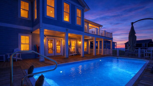 A two-story house with a swimming pool, a covered deck, and a view of the sunset. - Discover beachfront bliss at Starboard Side, Oak Island's spacious 4-bedroom retreat. (Oak Island)