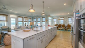 A spacious kitchen with a large island, modern appliances, and large windows. - Discover beachfront bliss at Starboard Side, Oak Island's spacious 4-bedroom retreat. (Oak Island)
