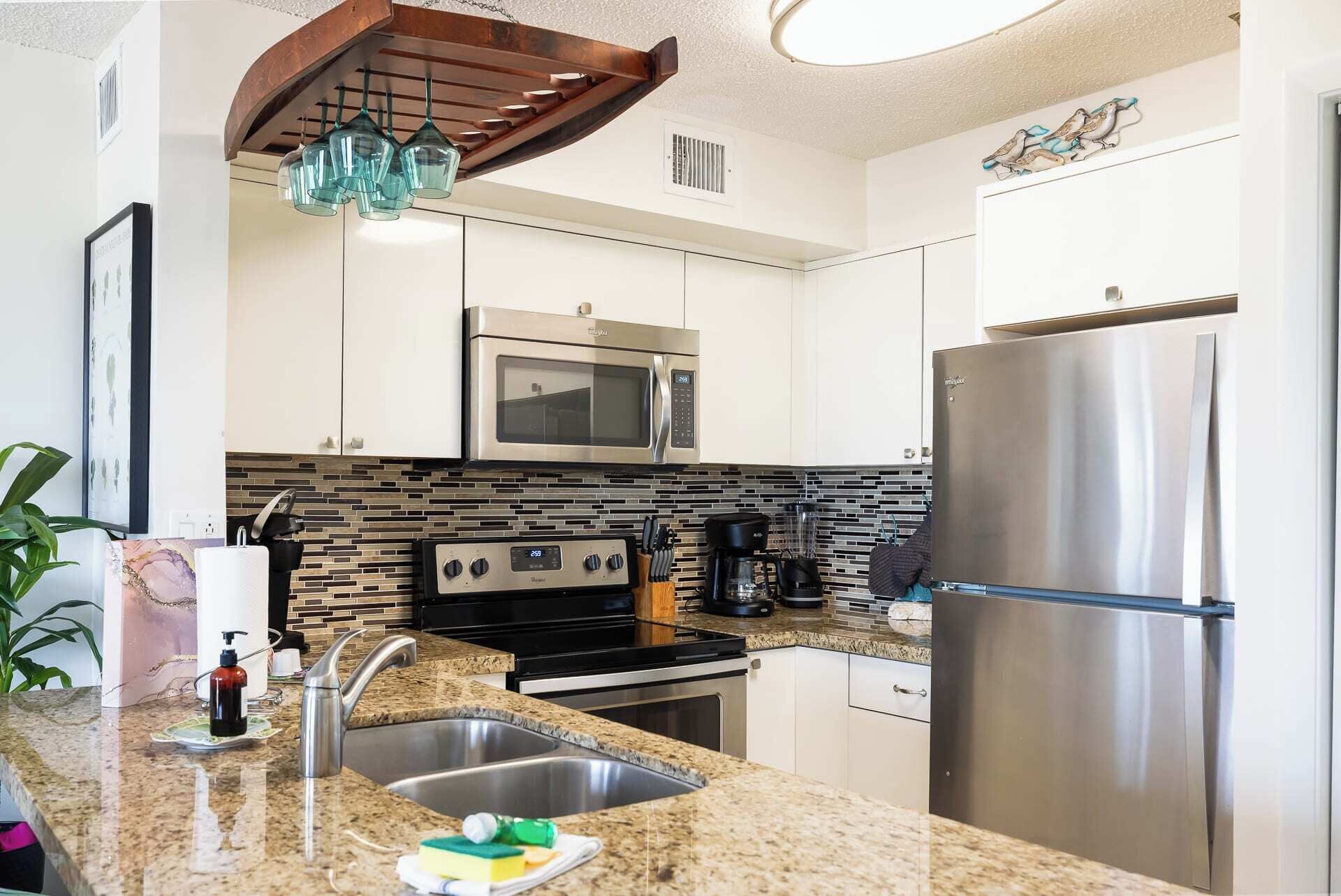A modern kitchen with stainless steel appliances, a granite countertop, and a backsplash with a mosaic tile pattern.